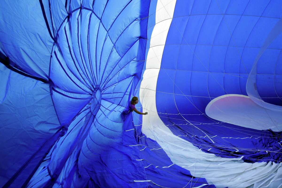 A crew member checks guide wires as a hot air balloon inflates for flight at the 32nd annual OuickChek New Jersey Festival of Ballooning Sunday, July 27, 2014, in Readington, N.J.