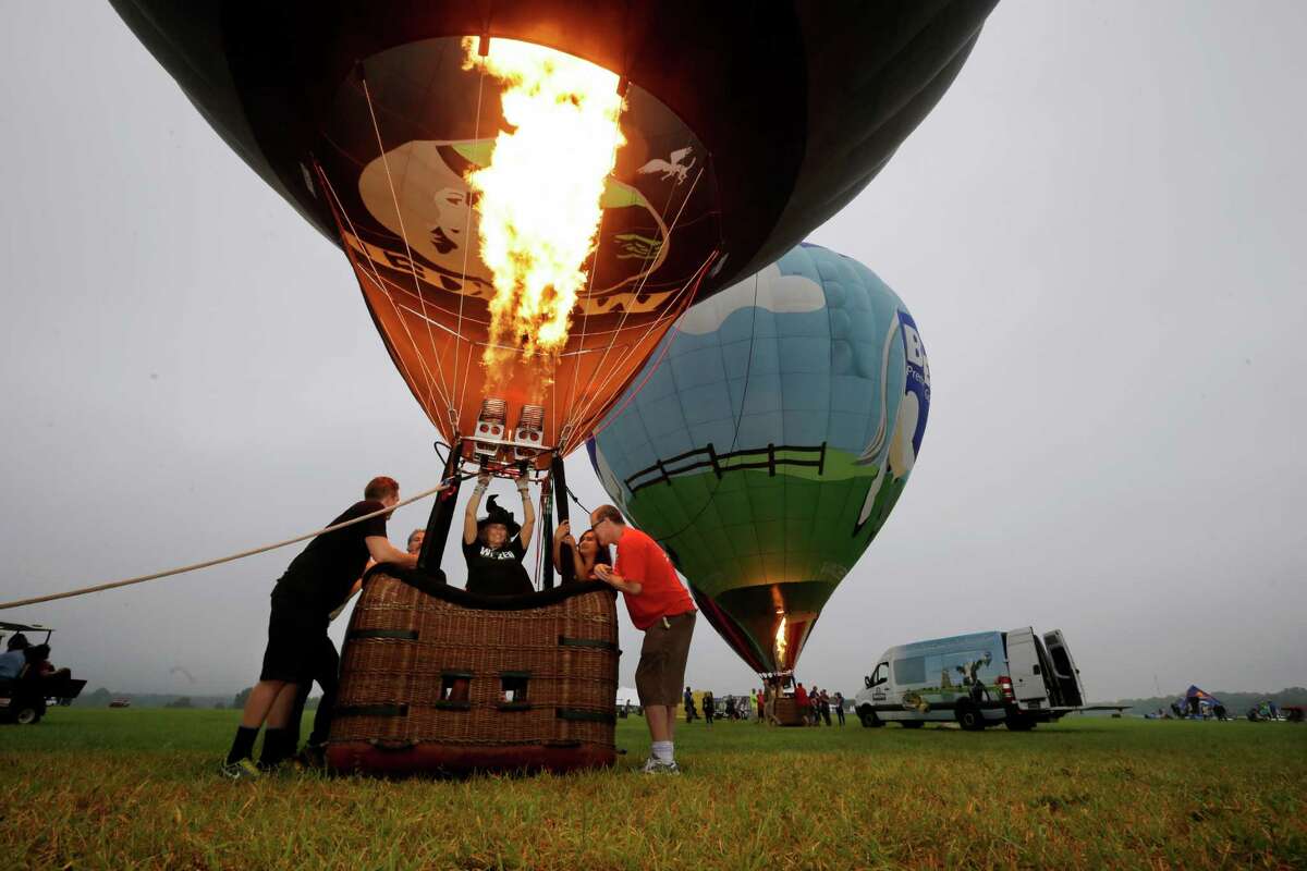Laura LiAnn Adams, of Elverson, Pa., wears a witch's hat as she inflates her hot air balloon, Wicked, for flight at the 32nd annual OuickChek New Jersey Festival of Ballooning Sunday, July 27, 2014, in Readington, N.J. 