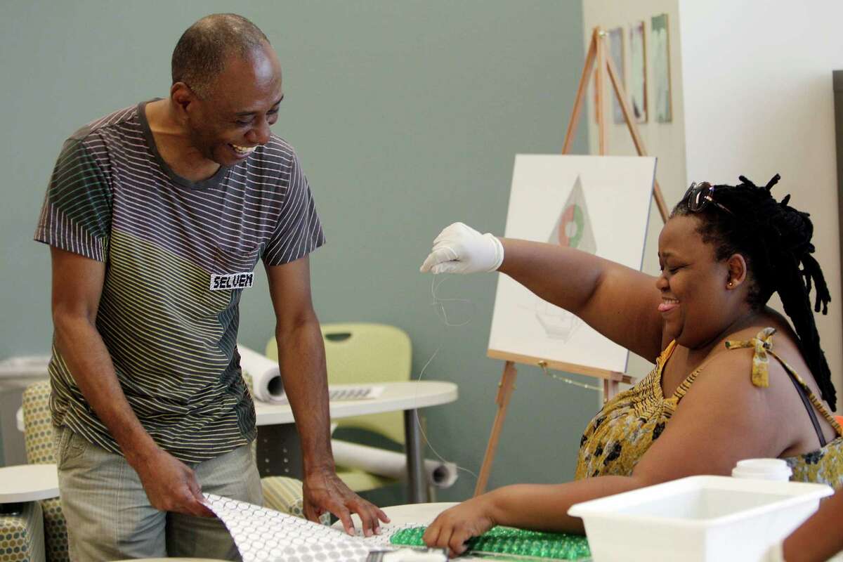 Artist Selven O'Keef Jarmon discusses beading with Bulelwa Bam, Director of Eastern Cape Craft Hub, while a collective of women from Eastern Cape bead thousands of green and white glass beads on a tapestries as part of the public art project "360 Degrees Vanishing" on July 23, 2014, in Houston. The public art project will cover the exterior walls of the Art League Houston building this Fall season. ( Mayra Beltran / Houston Chronicle )