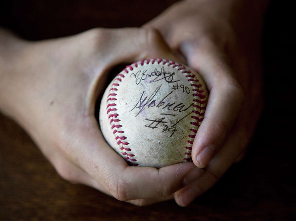 Mica Jarmel-Schneider holds a baseball signed by various Cuban players including Jose Abreu, who defected from Cuba in 2013 and was the AL Rookie of the Year for the White Sox in 2014.