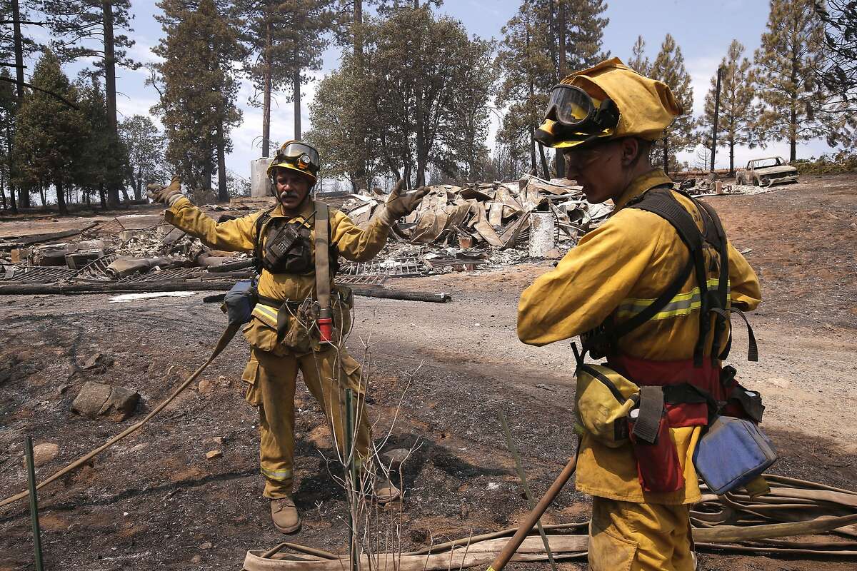 Firefighters David Harer, (left) and Jake Chesnut, with the Mariposa County fire department mop up after two homes were destroyed in the El Portal fire just west of Yosemite National Park on Tuesday July 29, 2014, in Foresta, Calif.