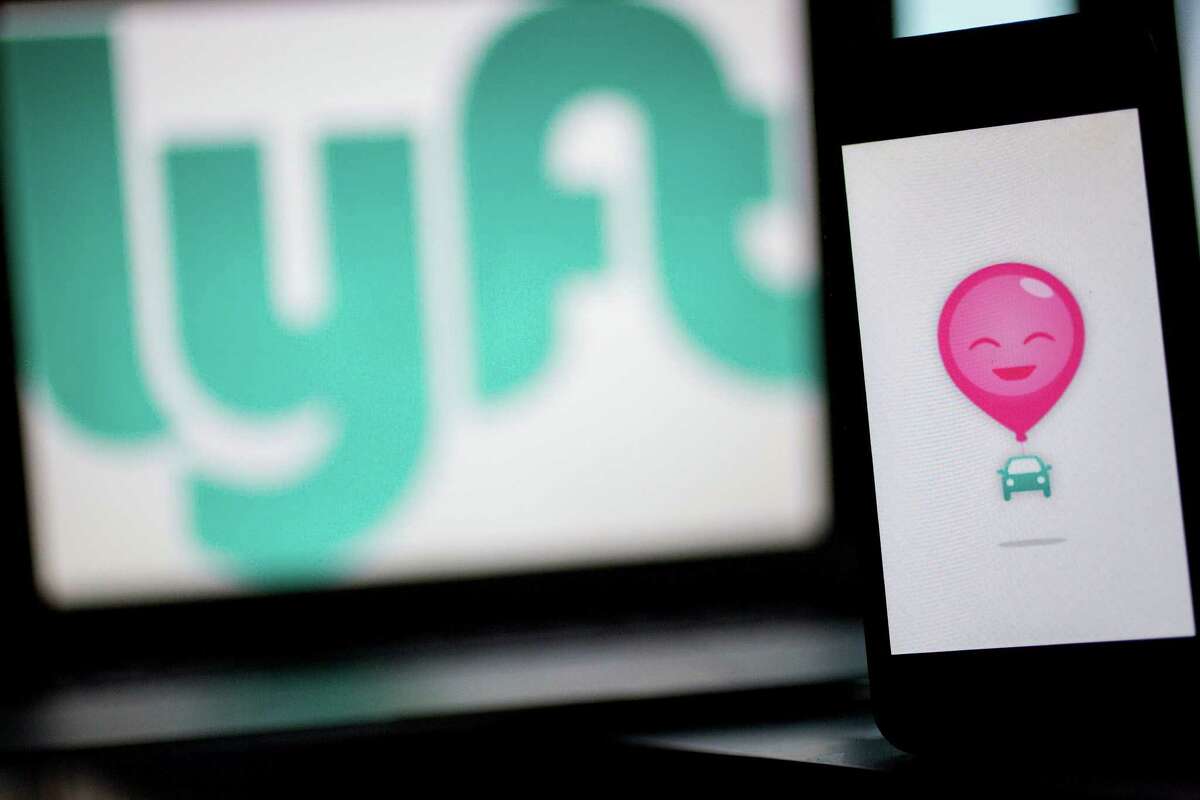 The Lyft Inc. logo and application (app) is displayed on an Apple Inc. iPhone 5s and MacBook Air for an arranged photograph in Washington, D.C., U.S., on Wednesday, July 9, 2014. Lyft Inc. is taking its ride-sharing service into New York this week and is abandoning its trademark pink mustaches in the process, taking on rival Uber Technologies Inc. in one of the biggest U.S. markets. Photographer: Andrew Harrer/Bloomberg