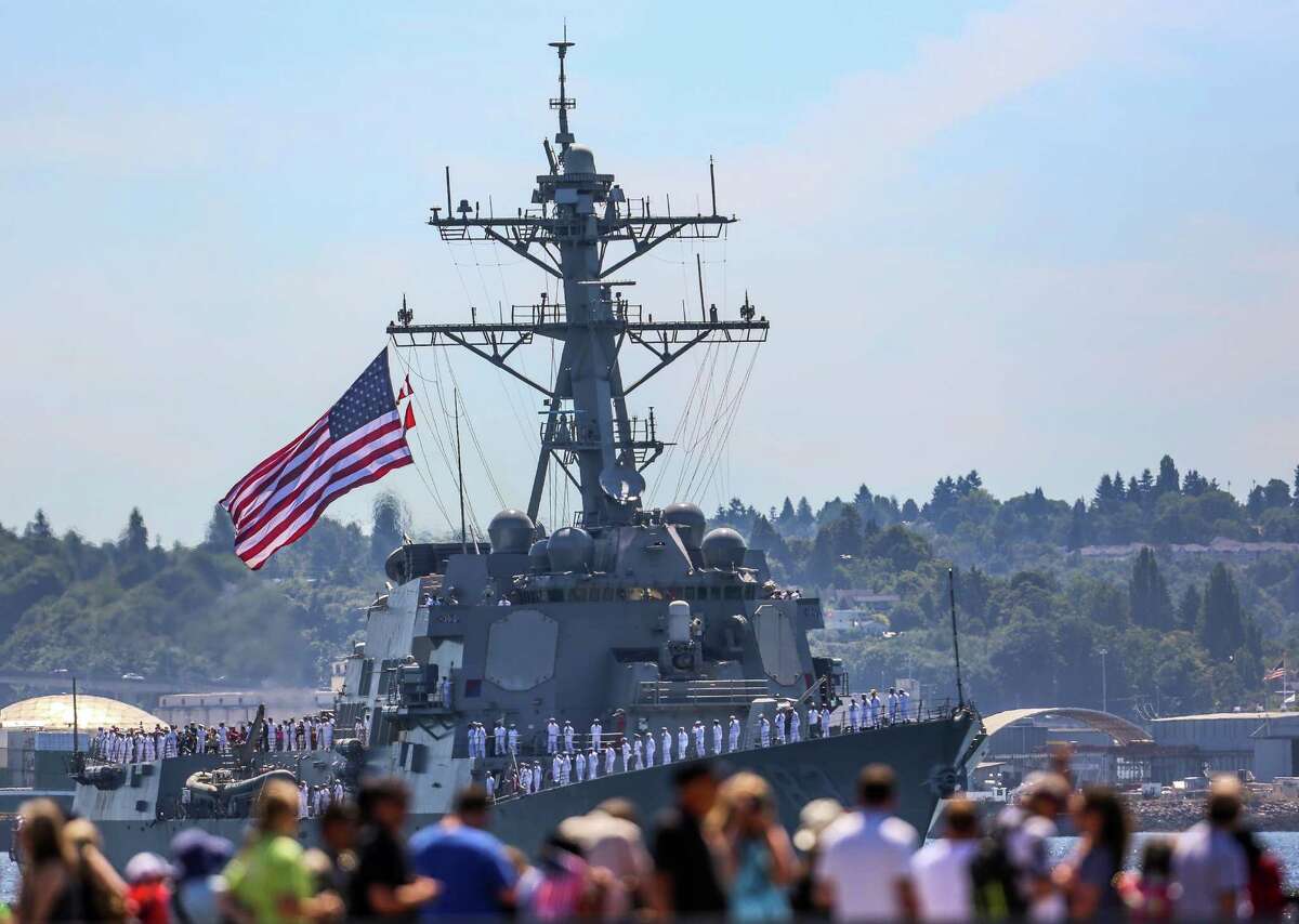 Spectators watch the USS Howard pass during the Seafair Parade of Ships & Flight. Hundreds of spectators lined up along Elliott Bay to watch the incoming ships and military flyovers on July 30, 2014.