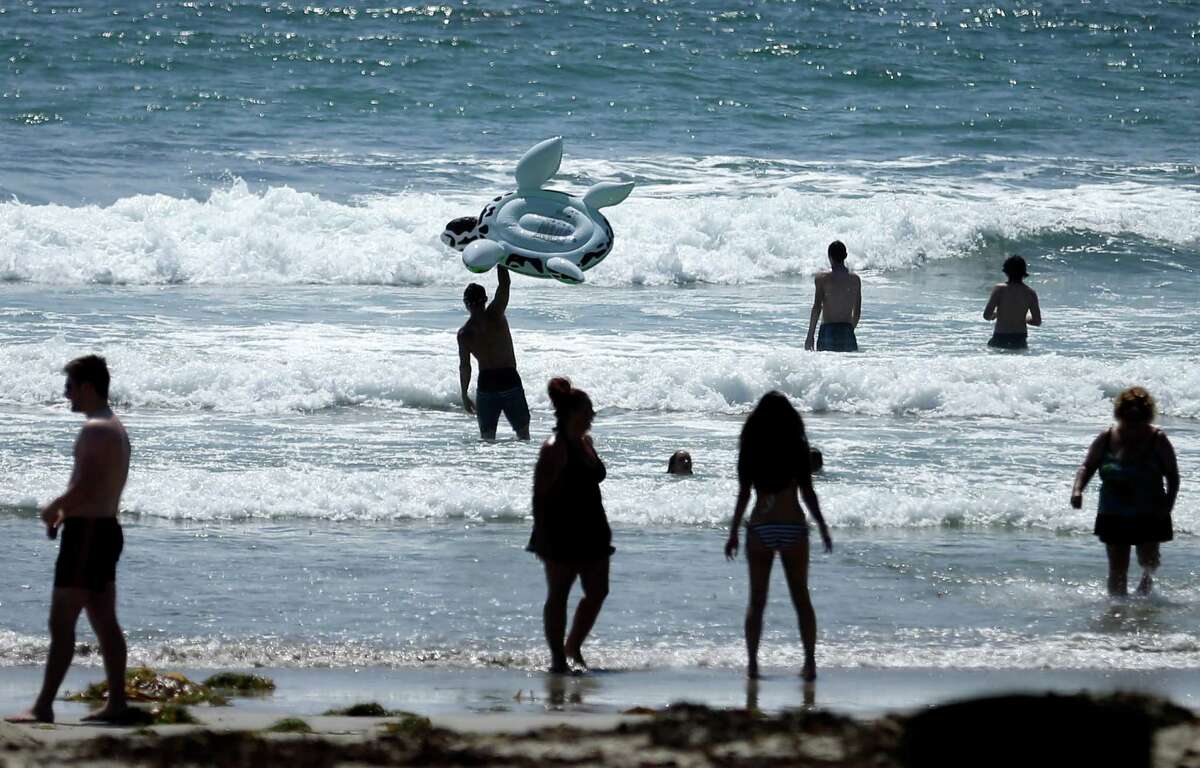 People swim on a sunny day at Mission Beach in San Diego, on Tuesday, June 24. Stop sunbathing and using indoor tanning beds, the acting U.S. surgeon general warned in a report that cites an alarming 200 percent jump in deadly melanoma cases since 1973. (AP Photo/Gregory Bull, File)