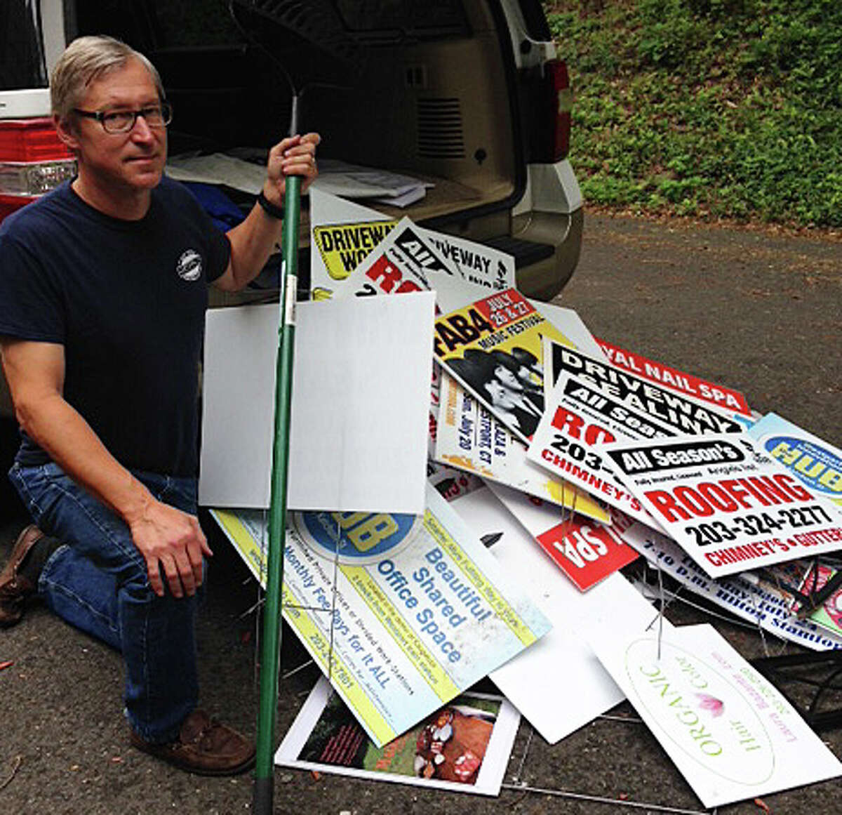 Planning and Zoning Commission member Alfred Gratix Jr., who with P&Z Chairman Chip Stephens is one of the "De-Signers," with a haul of illegally posted roadside signs the men recently took down.