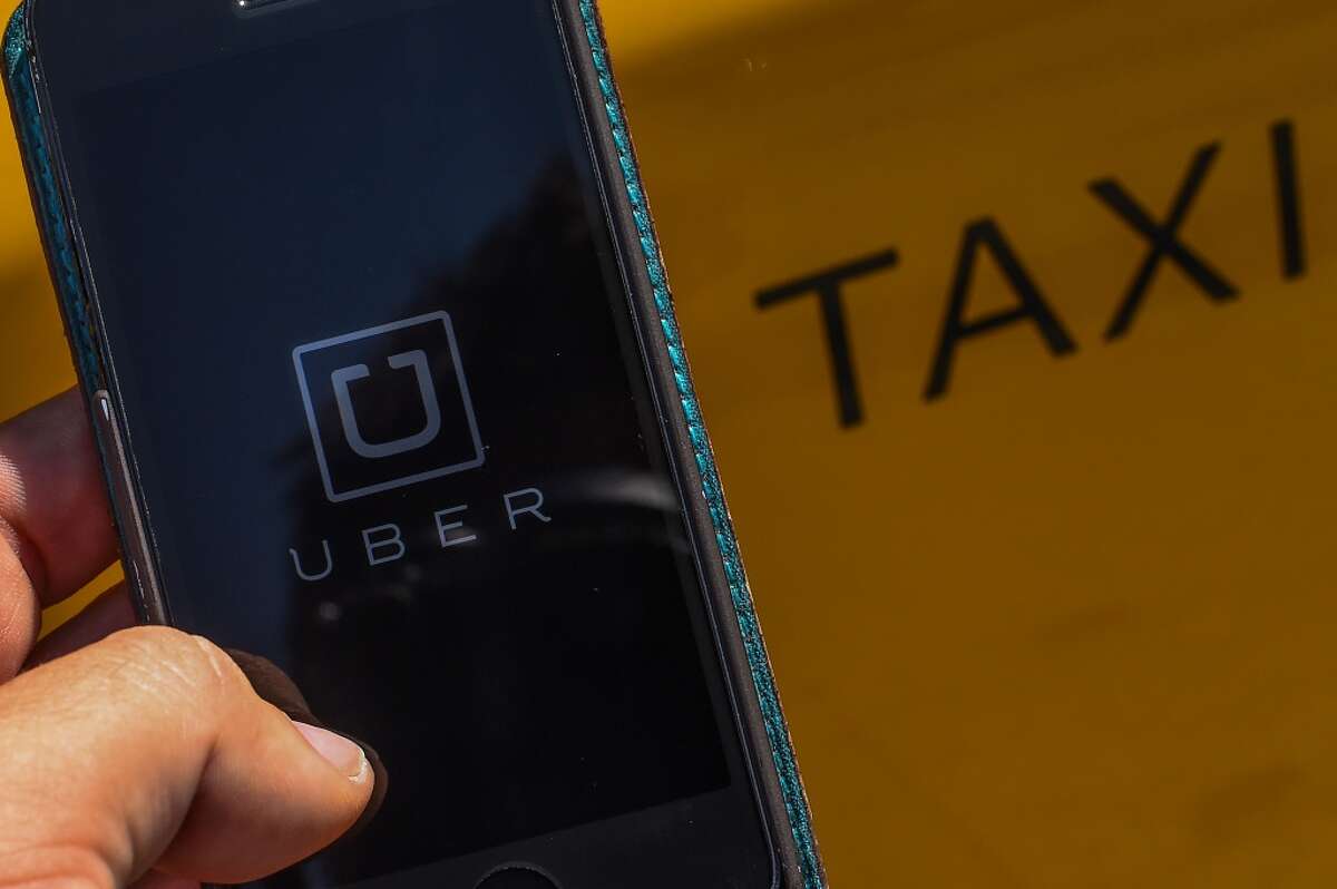 In this photo illustration, the new smart phone app 'Uber' logo is displayed on a mobile phone next to a taxi on July 1, 2014 in Barcelona, Spain.(Photo Illustration by David Ramos/Getty Images)
