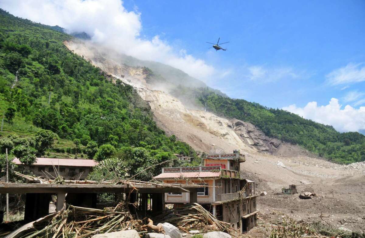 A Nepalese Army helicopter flies over the site of a landslide during a rescue operation in Sindhupalchowk area, about 120 kilometers (75 miles) east of Katmandu, Nepal, Saturday, Aug. 2, 2014. A massive landslide killed at least eight people and blocked a mountain river in northern Nepal on Saturday, causing the water to form a lake that was threatening to burst and sweep several villages, officials said. (AP Photo/Dinesh Gole)