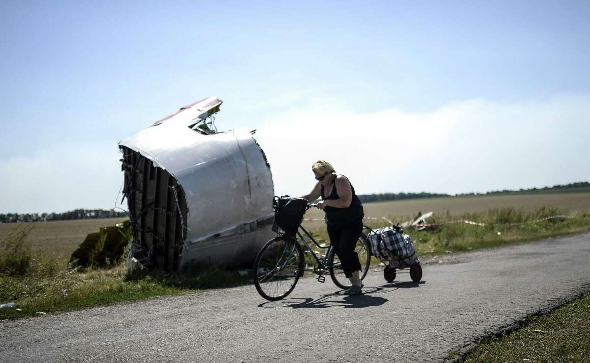 A woman walks with her bicycle near the crash site of the Malaysia Airlines Flight MH17 in the village of Hrabove, some 50 miles east of Donetsk, on Saturday.