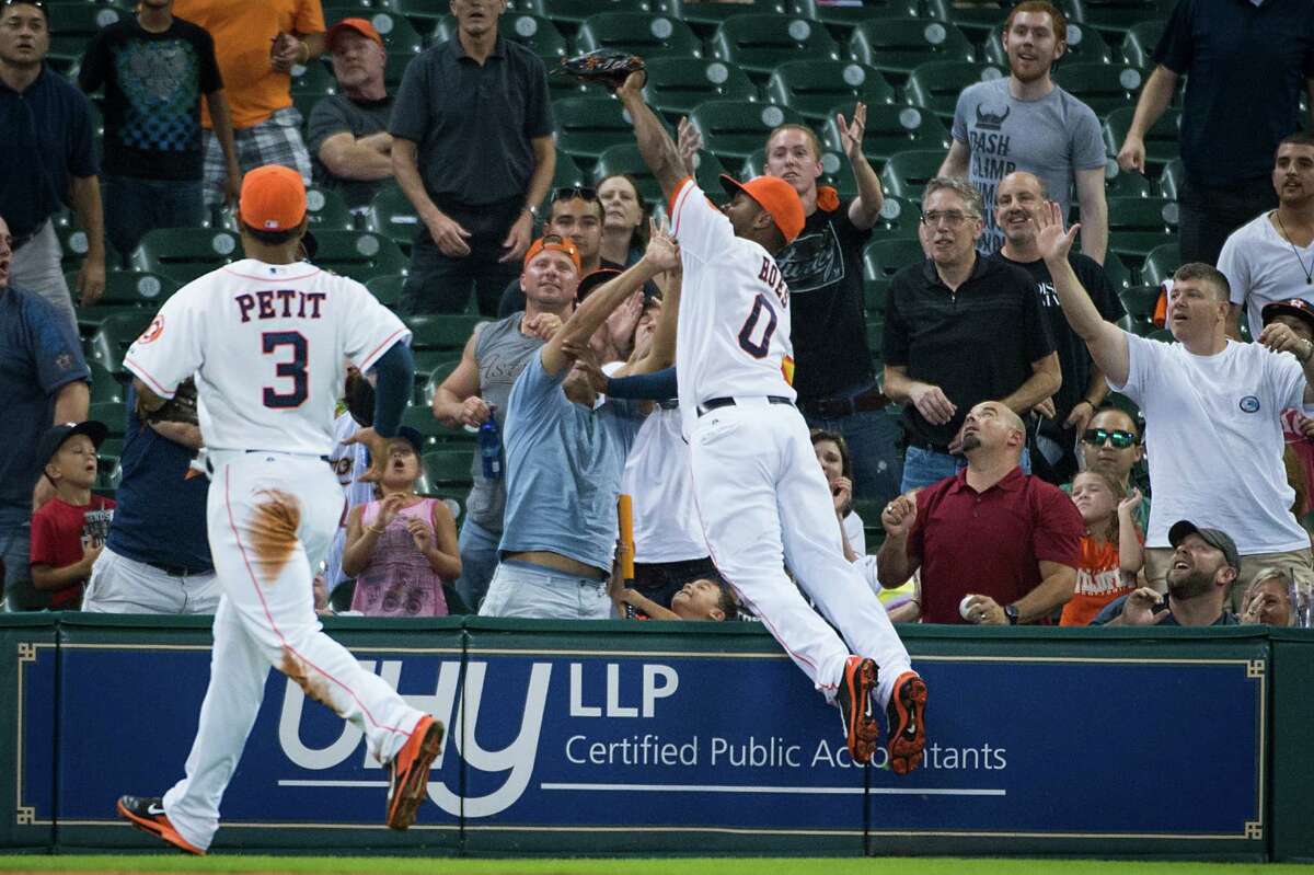 Astros left fielder L.J. Hoes leaps to catch a foul pop-up off the bat of Toronto pinch hitter Munenori Kawasaki before falling into the stands in the ninth inning of the Astros' 8-2 victory over the Blue Jays on Saturday.