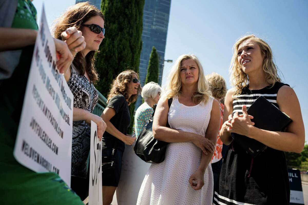 Clutching a MacArthur Study Bible, Heather, no last name given, right, speaks to former members of the Seattle-based Mars Hill Church at a self-titled "Peaceful Protest" Sunday, August 3, 2014, at the church's main site in Bellevue, Wash. The protest came about in regards to Mark Driscoll, pastor of Mars Hill Church, claiming he was confused as to how to reconcile with people who were 'hurt' by his actions because they are 'anonymous.'