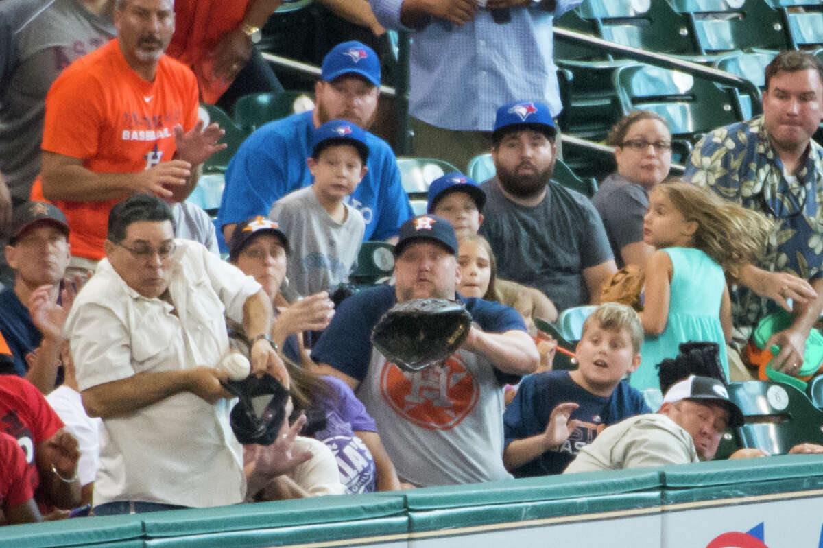 Necessity is the mother of invention as one fan turns his cap into a makeshift glove when trying to catch a foul ball off the bat of Astros outfielder Robbie Grossman during the third inning Sunday.