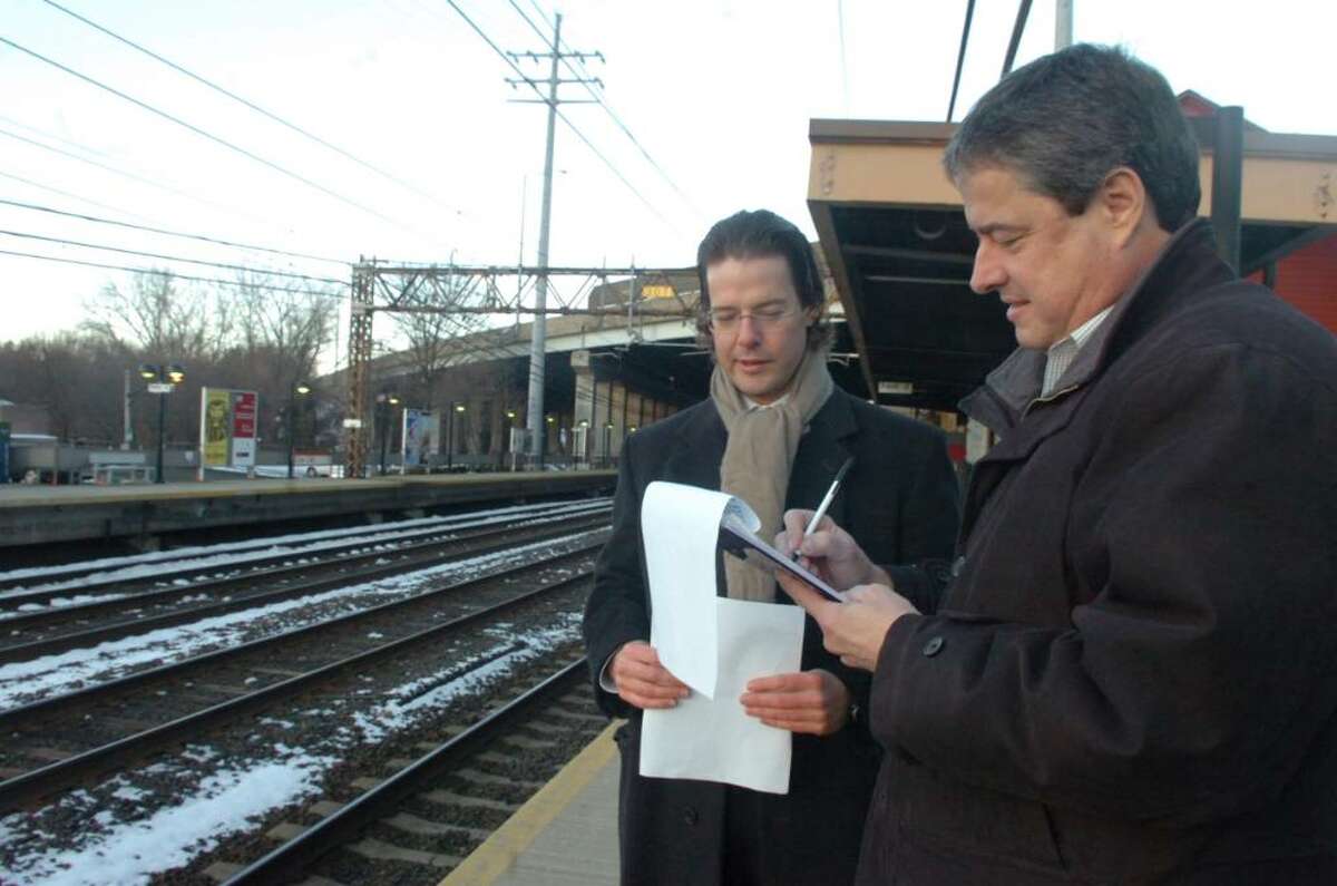 Wayne Jervis, left, convinces Victor Coutinho, right, to signs a petition to keep the cell tower further away from Cos Cob schools and residences at the Cos Cob railroad station, on Thursday, February 18, 2010.