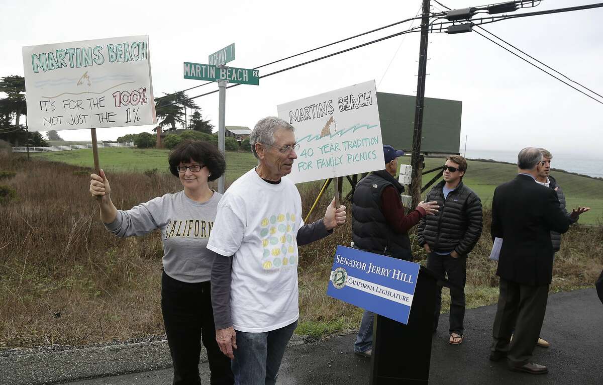 File - In this Feb. 10, 2014, file photo, Julie Graves, left, of Albany, Calif., and Chris Adams, second from left, of Berkeley, Calif., hold up signs in support of a beach access bill that Democratic state Sen. Jerry Hill introduced near Martin's Beach in Half Moon Bay, Calif. California's Coastal Commission is asking the public to document its use of Martin's Beach after billionaire landowner Vinod Khosla closed the only access road to it. (AP Photo/Eric Risberg, File)
