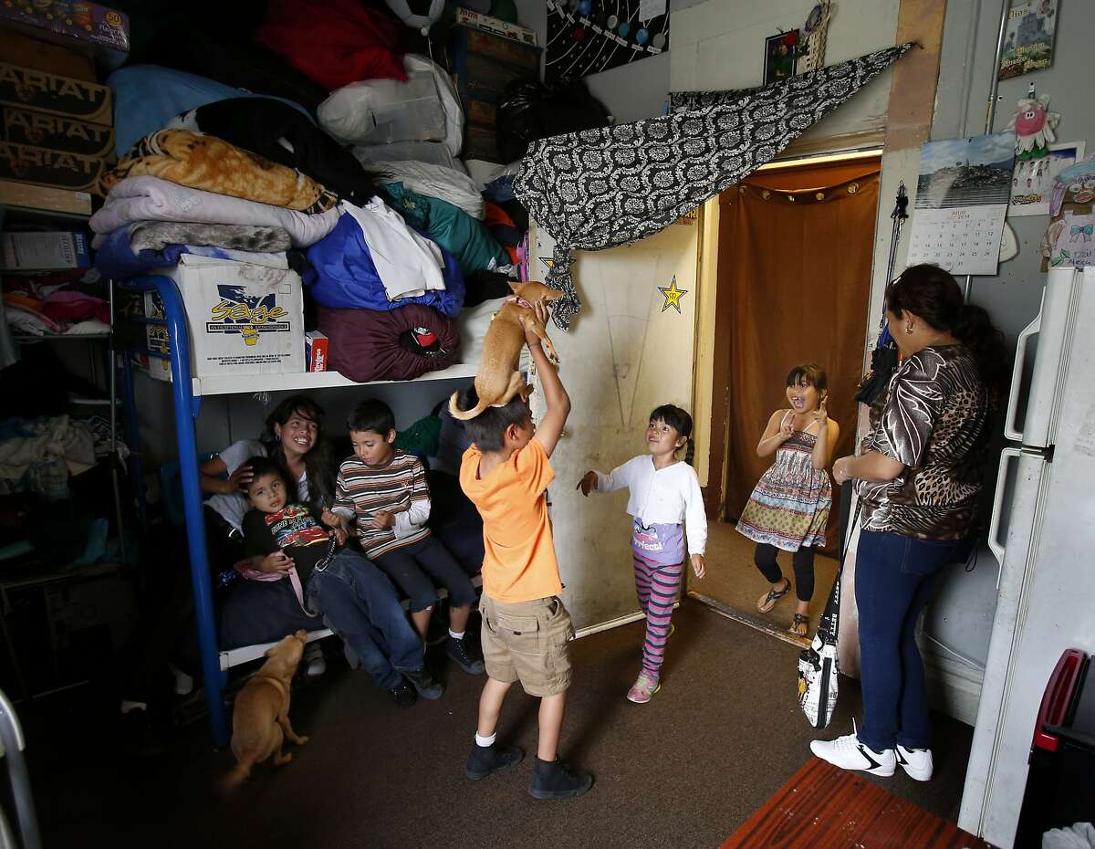 In their small living space, Laura Chinas and her children play with their dogs along with others who live in the building. The single room occupancy hotel on Mission Street has a history of complaints from residents.