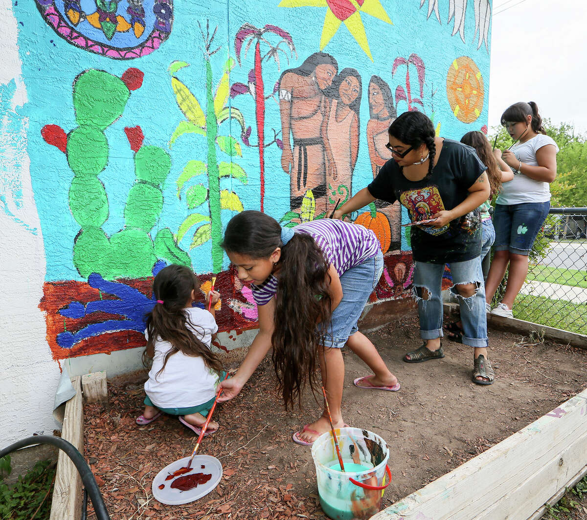 Gladys Moreno (from left), 5, Aricely Moreno, 9, Jane Madrigal, Penelope Lopez, 9, and Laila Smith, 10, paint a mural on the wall of a buidling in the Children's Jr Master Gardners program at Time Dollar, 2806 W. Salinas, on Friday, Aug. 1, 2014. MARVIN PFEIFFER/ mpfeiffer@express-news.net