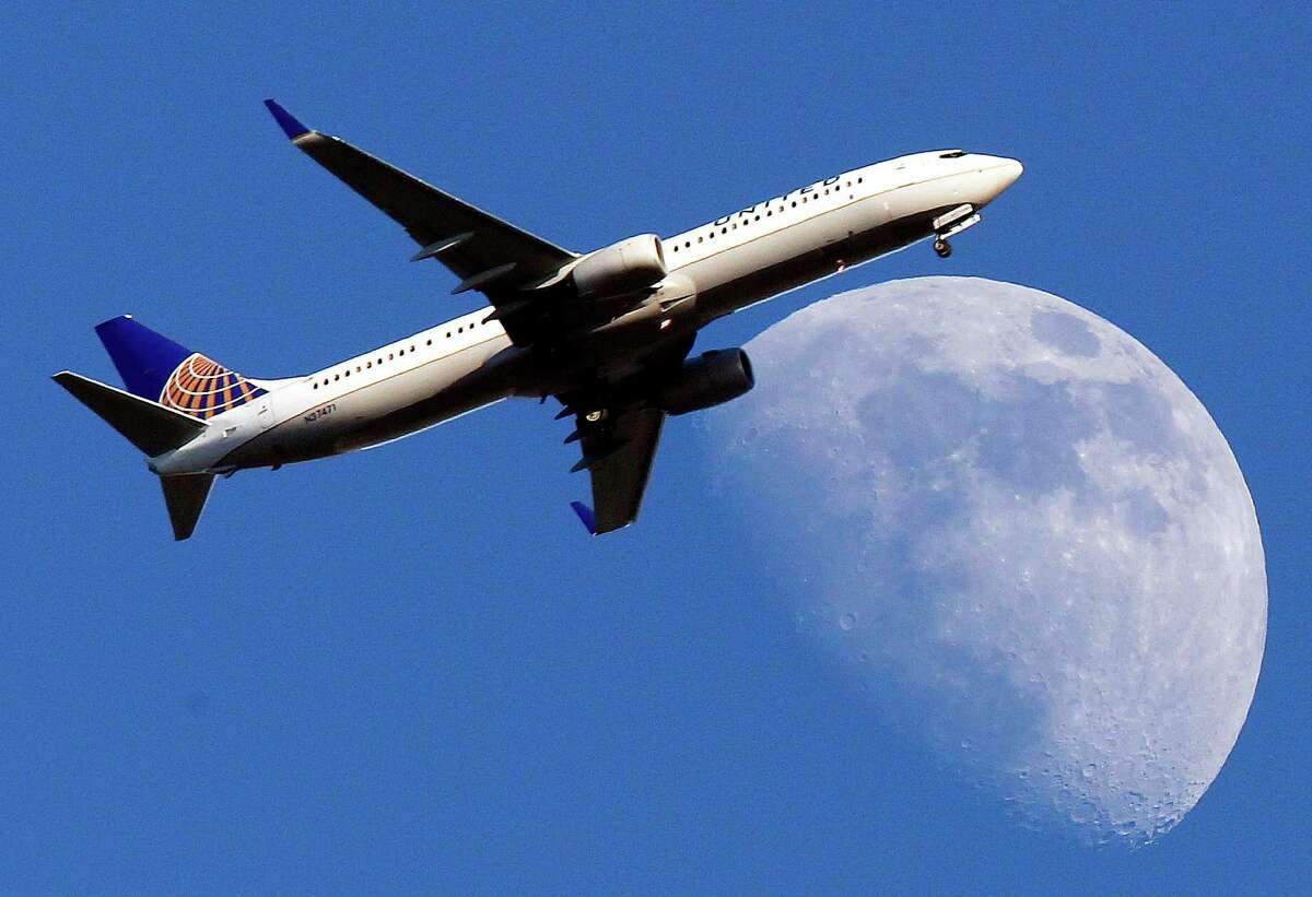 A United Airlines jet passes in front of a Waxing Gibbous moon in this July 17, 2013 file photo. ( AP Photo/Nick Ut, File)