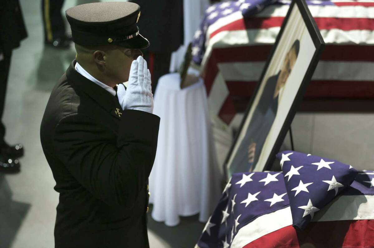 A fire honor guard member pays his respects in front of the coffin of one of the firefighters killed responding to the blast.