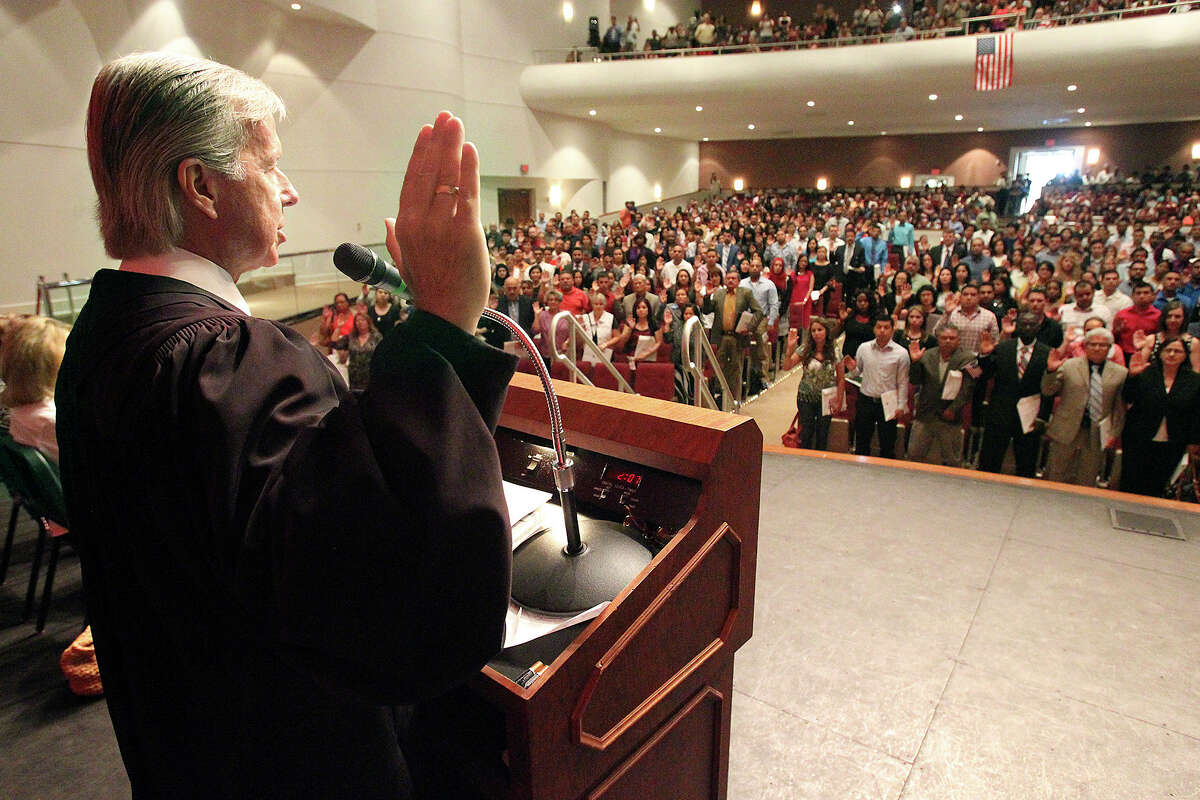 U.S. Magistrate Judge John Primomo presides over the naturalization ceremony for a group of 500 new citizens at the Edgewood Academy's Theatre of Performing Arts on July 31, 2014.