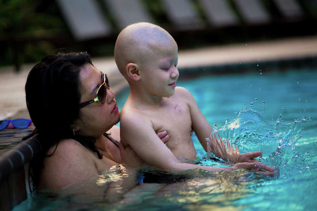 Luis Benicio De Matos, right, 5, plays with the water in the arms of his mother Cristiane De Matos, during a break from the cancer treatment Luis Benicio is receiving at the MD Anderson Cancer Center in Houston. The family, which are original from Brazil, arrived full of hopes to Houston, putting the fragile health of their son in the hands of the professionals of MD Anderson. Thursday, Aug. 7, 2014, in Houston. ( Marie D. De Jesus / Houston Chronicle )