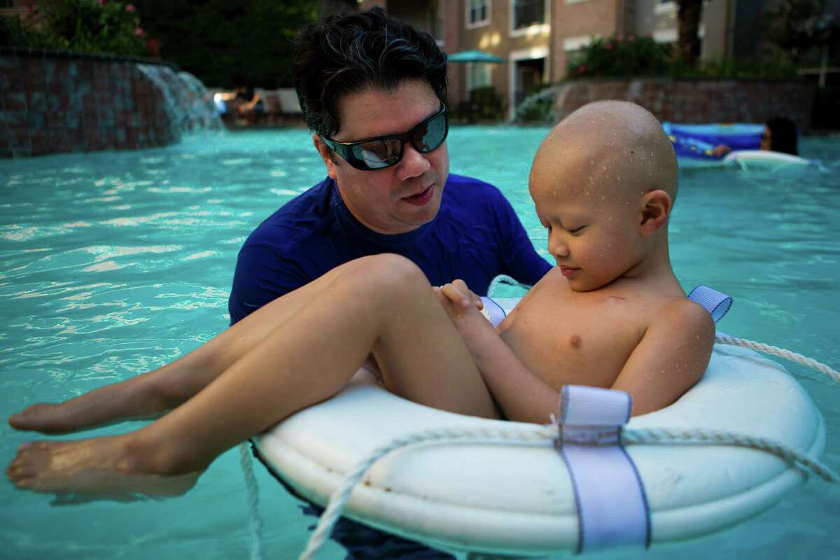 Caio De Matos of Brazil, keeps his son Luis Benicio De Matos, 5, on a floater as a way to keep him from submerging concerned for the fragile port installed on his son's chest. Caio De Matos and his wife have tried their best to treat the visit to Houston as a vacation for their family instead of an strict medical visit to MD Anderson where his son is currently receiving proton therapy for his malignant tumor. The therapy at MD Anderson was highly recommended by De Matos oncologists in Brazil. Thursday, Aug. 7, 2014, in Houston. ( Marie D. De Jesus / Houston Chronicle )