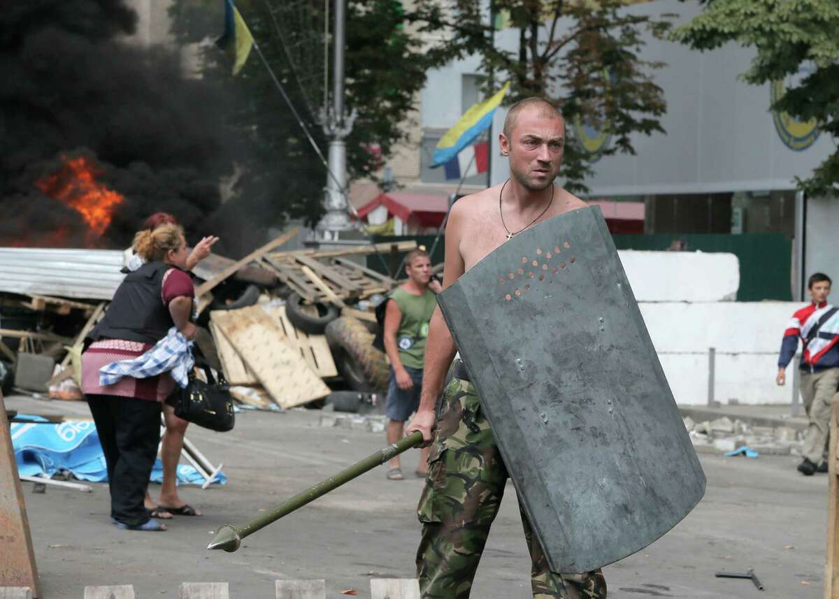The dweller of the tent camp that has blocked the main street of Ukraine's capital since protests that toppled the government earlier this year, stands guard as volunteers arrive to clear the square in Kiev, Ukraine, Saturday, Aug. 9, 2014. Protesters erected the barricades to protect a sprawling tent camp on the central city's main square. Although the camp's size dwindled sharply after President Viktor Yanukovych fled the country in February and a new government came to power, a determined core of demonstrators remained in a show of suspicion of the new authorities. Some tents remained on Saturday. But Kiev mayor Vitali Klitschko, who was one of the leaders of the protests against Yanukovych, was quoted by Ukrainian media as saying an agreement has been reached with the protest holdouts to restore free movement in the center.