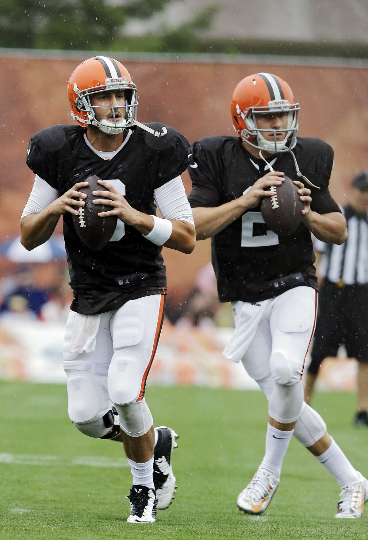 Cleveland Browns quarterbacks Brian Hoyer, left, and Johnny Manziel drop back to pass during practice at NFL football training camp in Berea, Ohio on Monday, Aug. 11, 2014. (AP Photo/Mark Duncan)