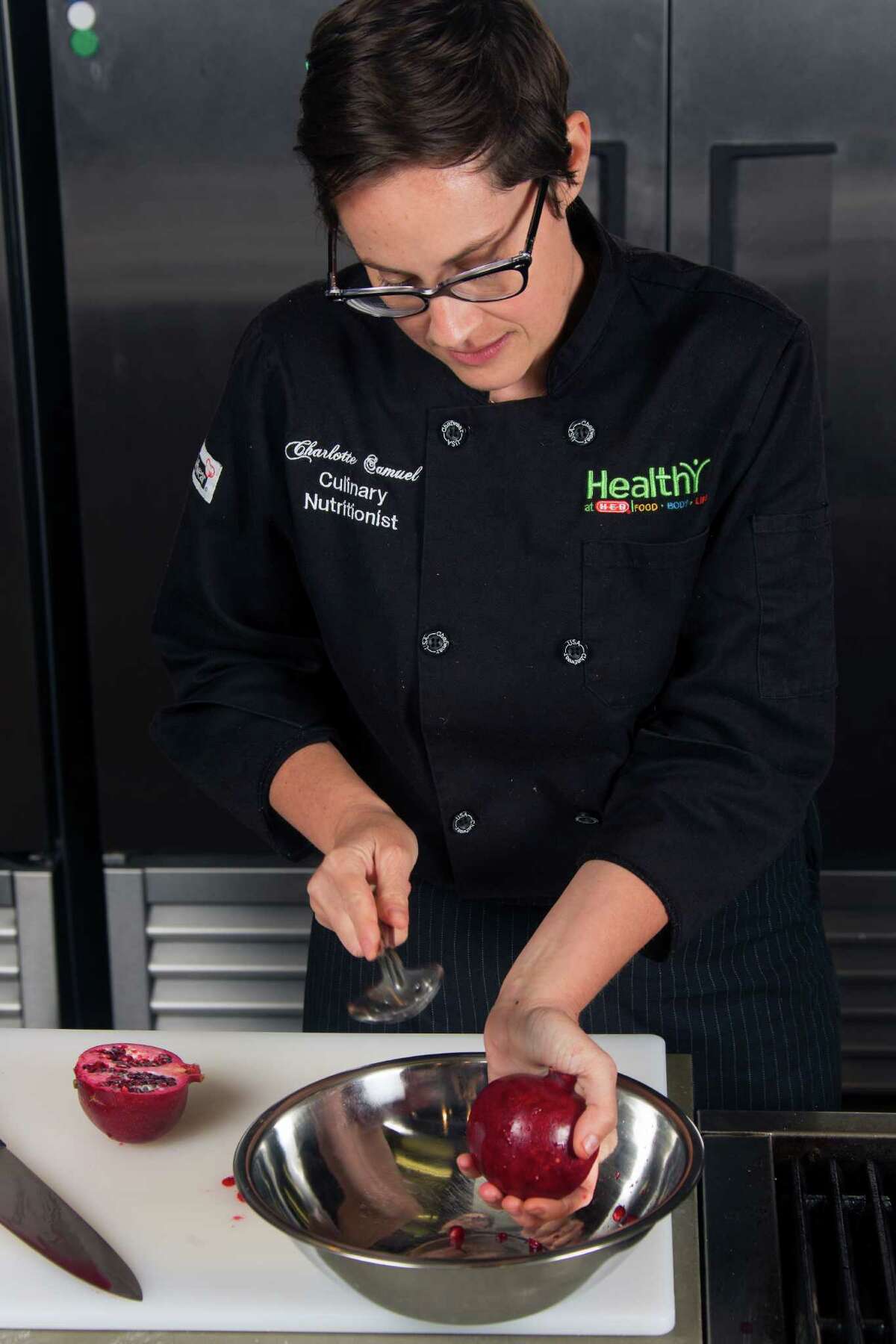 After cutting the fruit in half, HEB Chef Charlotte Samuel removes the seeds from a pomegranate Tuesday July 29, 2014 by banging on the outside of the fruit with a heavy spoon which makes the seeds fall out.