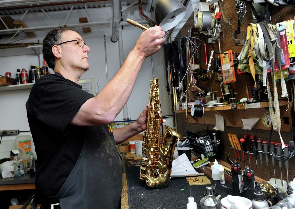 Bruce Treidel, 58, repairs an alto sax Monday, August 11, 2014. Bruce and his wife, Dana, 56, are owners of the Bethel Music Center on Greenwood Ave. in Bethel. They are celebrating 30 years in business.