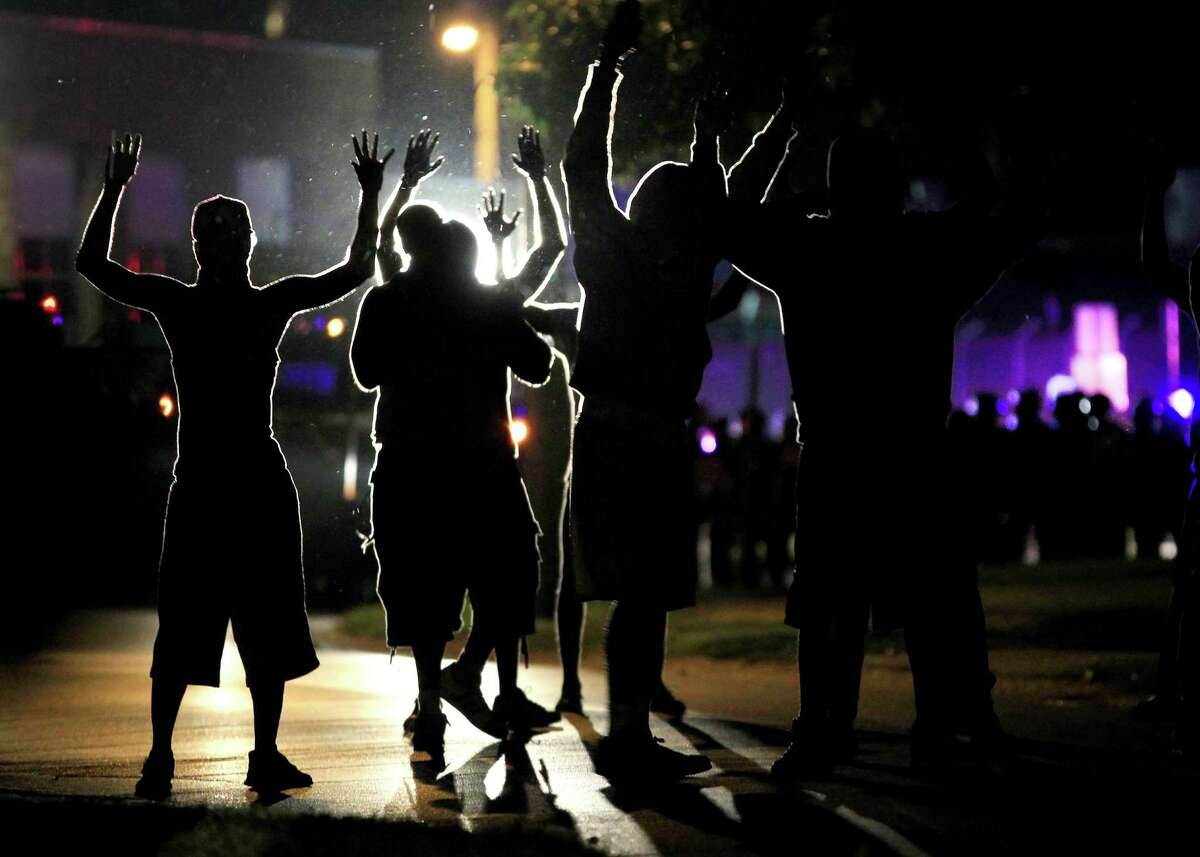 Aug. 11: Police respond with tear gas The FBI opens an investigation into Brown's death, and two men who said they saw the shooting tell reporters that Brown had his hands raised when the officer approached with his weapon and fired repeatedly. That night, police in riot gear fire tear gas and rubber bullets to try to disperse a crowd. Above, protesters raise their hands in the middle of the street as police wearing riot gear move forward to get them to disperse.