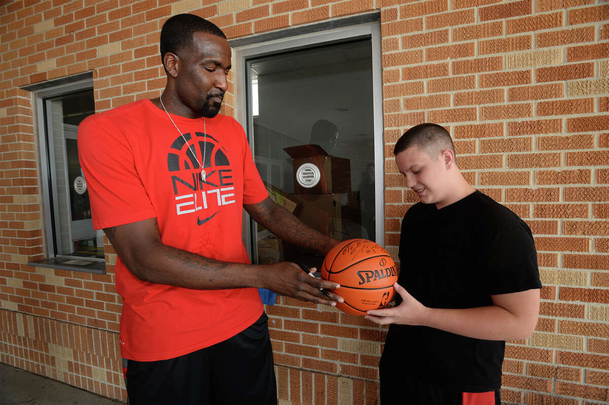Basketball star Kendrick Perkins hands a signed ball to William Barton's after the two met at Ozen on Tuesday. Barton, who is autistic, also received a signature on his Perkins-rookie card and a signed jersey. Photo taken Tuesday, August 12, 2014 Guiseppe Barranco/@spotnewsshooter
