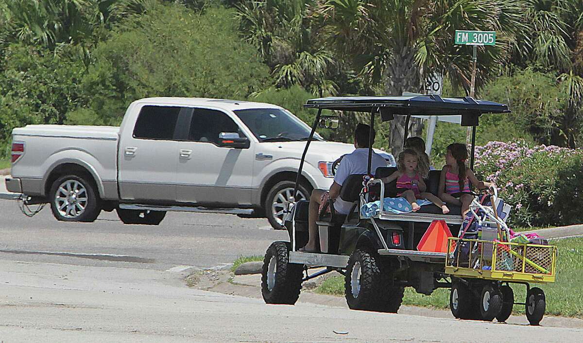 A golf cart with an extra trailer carries a family on a weekend jaunt in the Pirates Beach subdivision last Saturday.