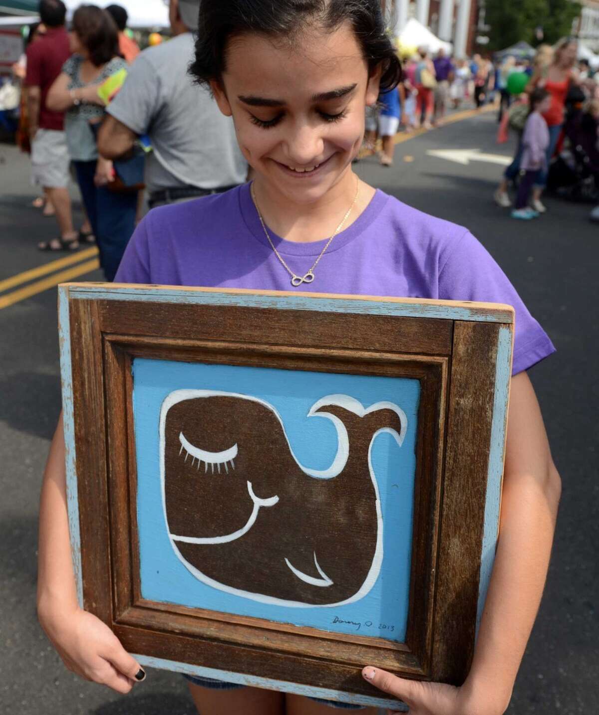 Emily Lobosco, 12, of Tampa Fla., visiting family in Norwalk, carries her newly purchased painting, by artist Daniel "Danny O" O'Connor, during the 38th annual SoNo Arts Celebration Saturday, Aug. 3, 2013 in Norwalk's Historic District at S. Main and Washington streets.