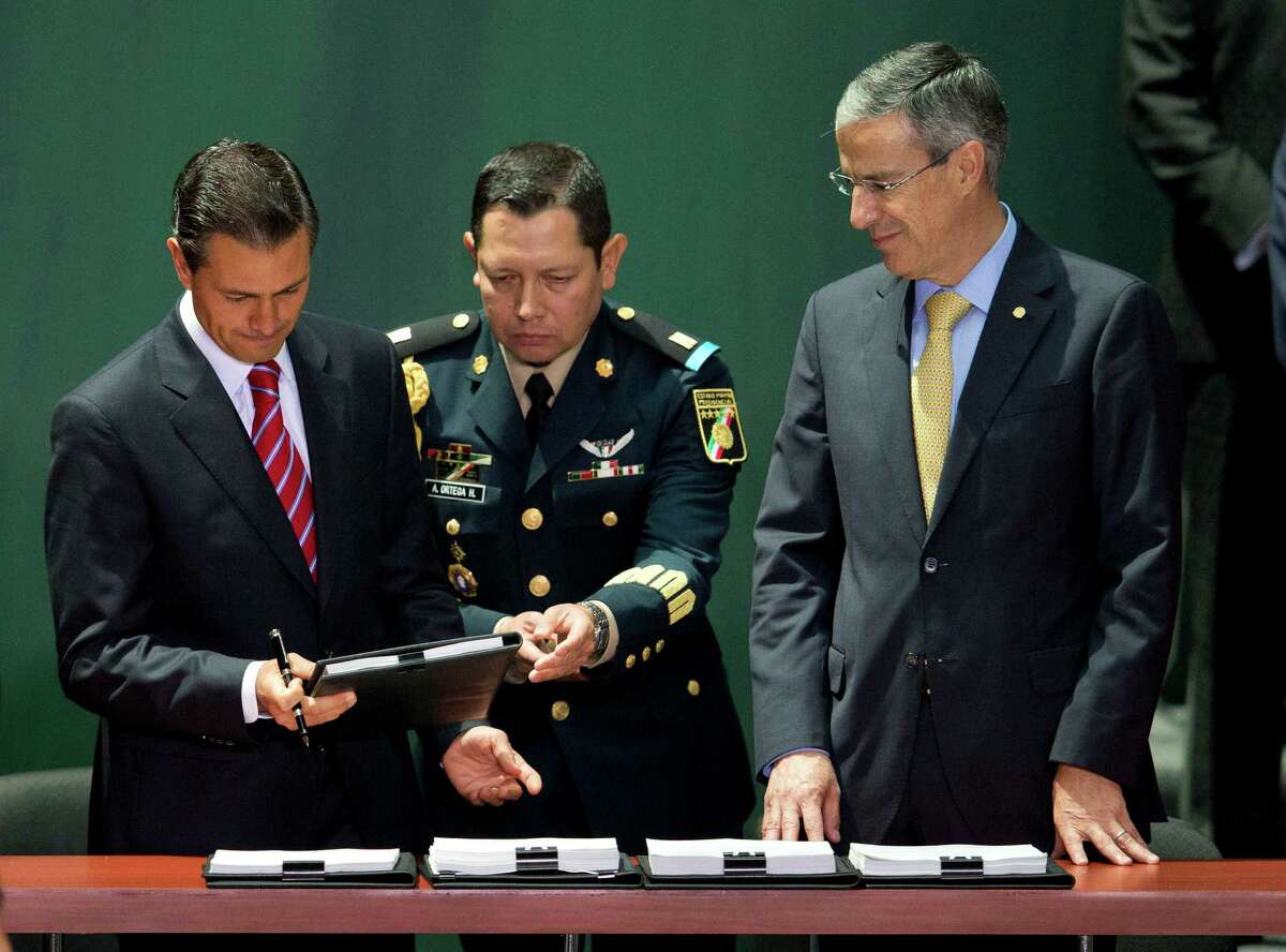 Mexican President Enrique Peña Nieto, left, is accompanied by House Speaker Jose Gonzalez Morfin, right, as he signs into law the nation's energy reforms at Mexico City's National Palace.