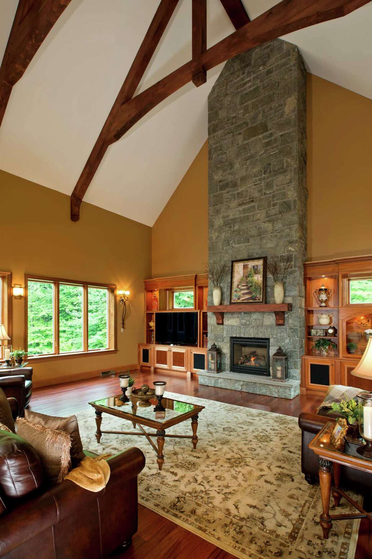 Stone fireplaces made with rocks with their natural look intact make for beautiful fireplaces, and since it looks good and this is your dream home, why not take up to the top of your vaulted ceiling like the one in this Taymor Trail home by Bella Home Builders?