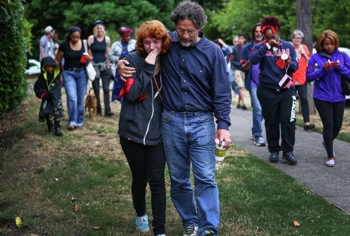 Meridian Smith, 18, is comforted by her dad, Doug Smith during a National Moment of Silence against police brutality at Queen Anne Baptist Church on Thursday, August 14, 2014. "It's strange that this can happen in the world we live in," the younger Smith said. Dozens gathered simultaneously at Queen Anne Baptist Church and at Westlake Park in Seattle. Across the country, people gathered to participate in the moments of silence after recent violence in Ferguson, Missouri and the shooting death of unarmed Mike Brown, a black man killed by a police officer there.