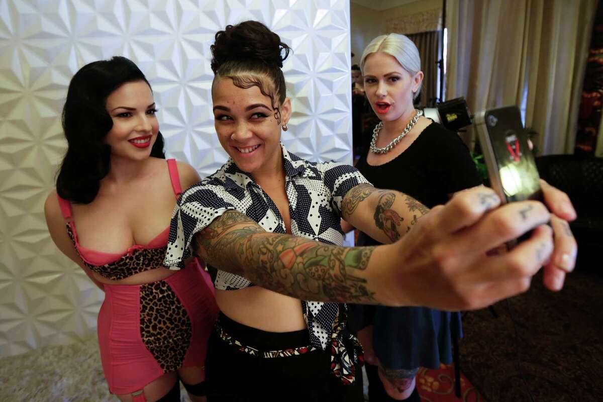 Stylist Madison Jane, center, takes a picture with Olivia Felix, left, as Melyssa Maria, right, looks on after a photo session during Tiki Oasis event Friday, Aug. 15, 2014, in San Diego. Hundreds of tiki culture aficionados, clad in tropical colors, gathered Friday for a weekend-long celebration that revels in the movements from the 1950s and 1960s. 