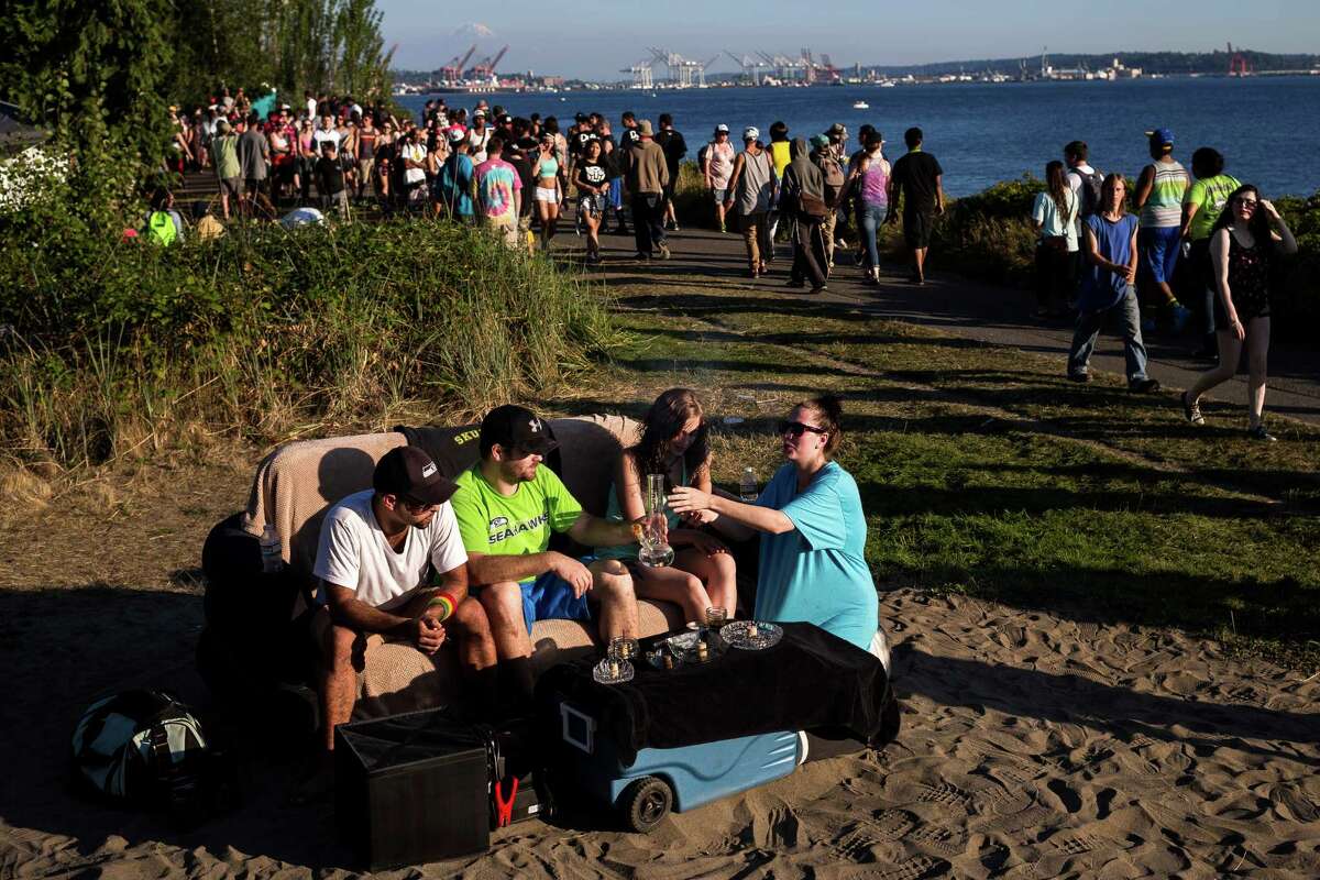 From left, Tommy Tompson and Jake Rossi, owners of Jettrays, share their bong with Darci Board and Desiree Dell from their seat on a portable, inflatable couch with a view of Mount Rainier in the background on the final day of Hempfest, Seattle's annual gathering to advocate the decriminalization of marijuana, photographed Sunday, August 17, 2014, at Myrtle Edwards Park on the Seattle waterfront in Seattle, Washington. The three-day annual event includes political rallies, concerts, and an arts and crafts fair.