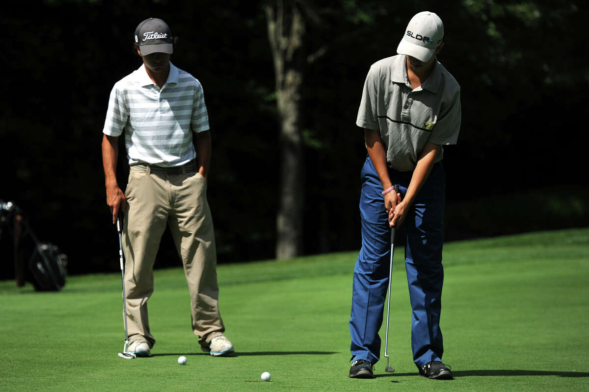 Kyle Poeti, of New Milford, sinks a putt during the Fran McCarthy Junior Golf Tournament at the Richter Park Golf Course, in Danbury, Conn. Aug. 18, 2014. Poeti is seen here with Alec Knupp of Ridgefield.