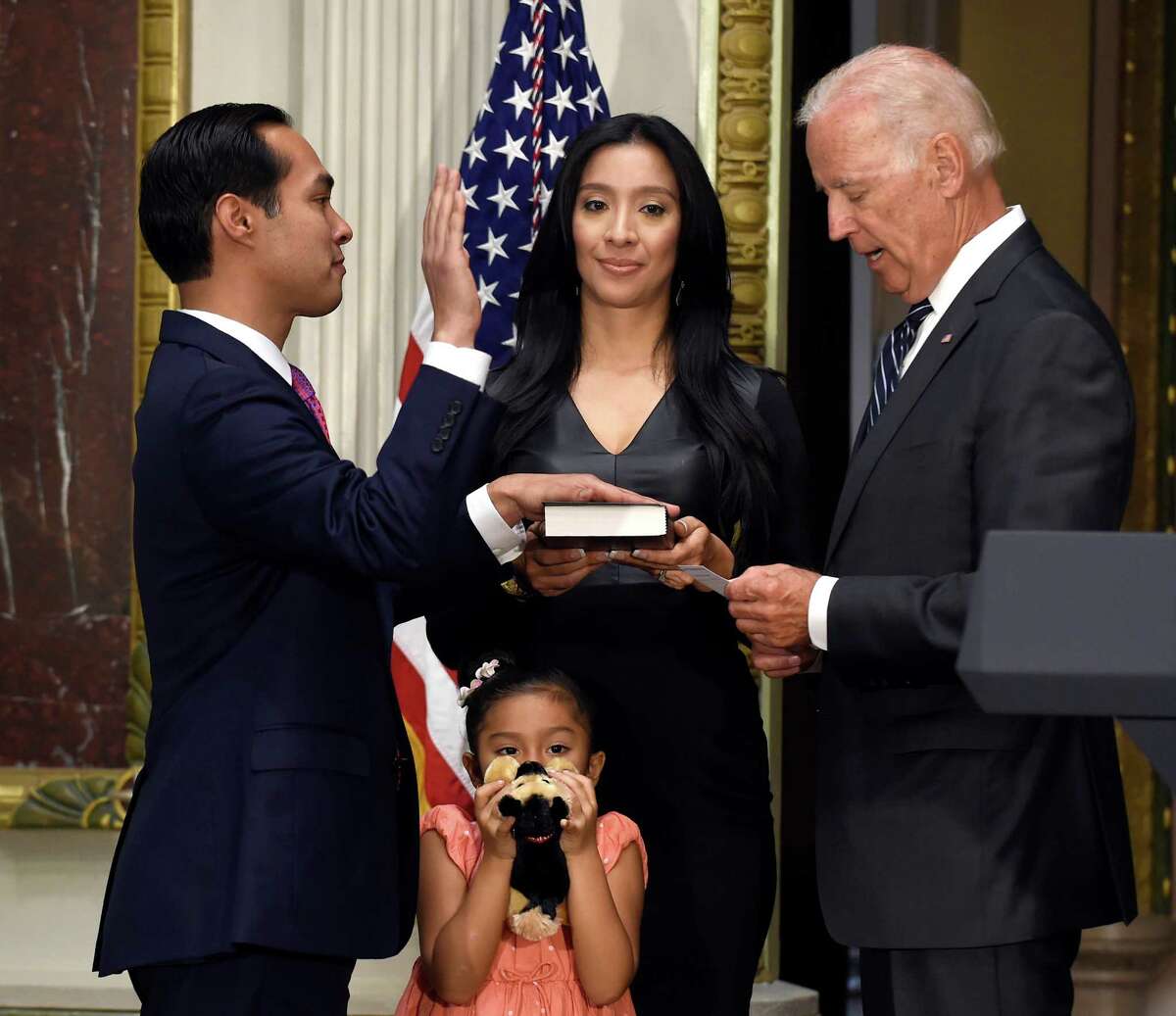 Then-Vice President Joe Biden ceremonially swears in Julian Castro, left, as Housing and Urban Development Secretary, Monday, Aug. 18, 2014, in the Eisenhower Executive Office Building on the White House complex in Washington. Castro's wife Erica Castro, holds the bible as his daughter, Carina Castro, center bottom, listens.