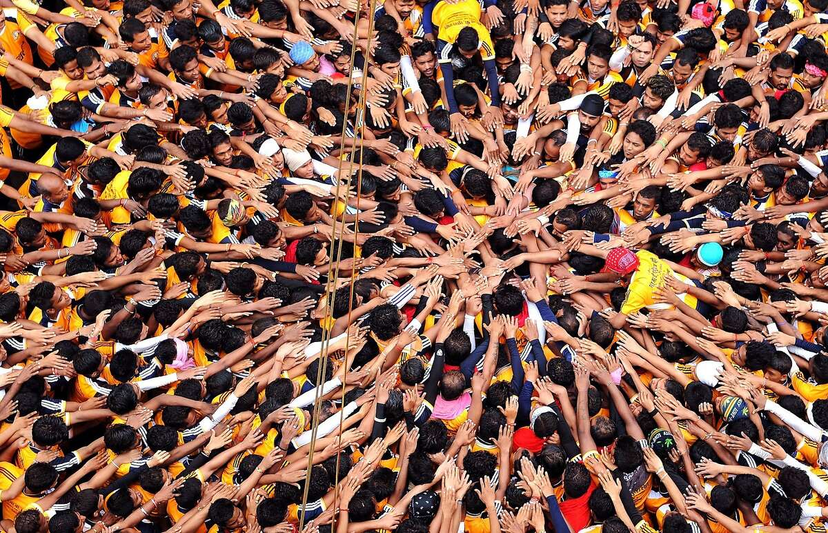 Pyramid scheme: Hindu devotees gesture before attempting to form a human pyramid in a bid to reach and break a dahi-handi (curd pot) suspended in air during celebrations for the Janmashtami festival in Mumbai. The winning team receives prize money.