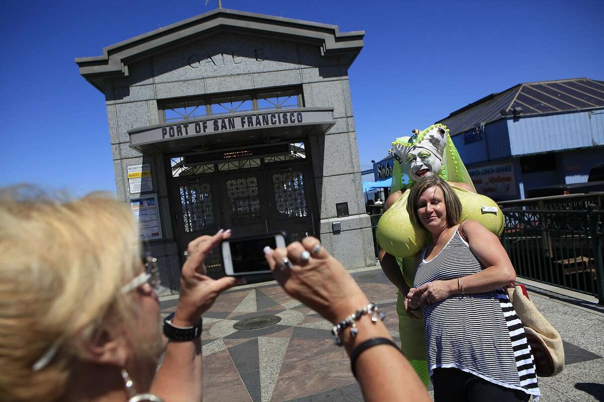 Visiting from Denver, Susie Marley takes a picture of her friend Michelle Hall with Sister Saki Tumi of the Sisters of Perpetual Indulgence in front of the SF ferry terminal in San Francisco, CA, Saturday, August 16, 2014.
