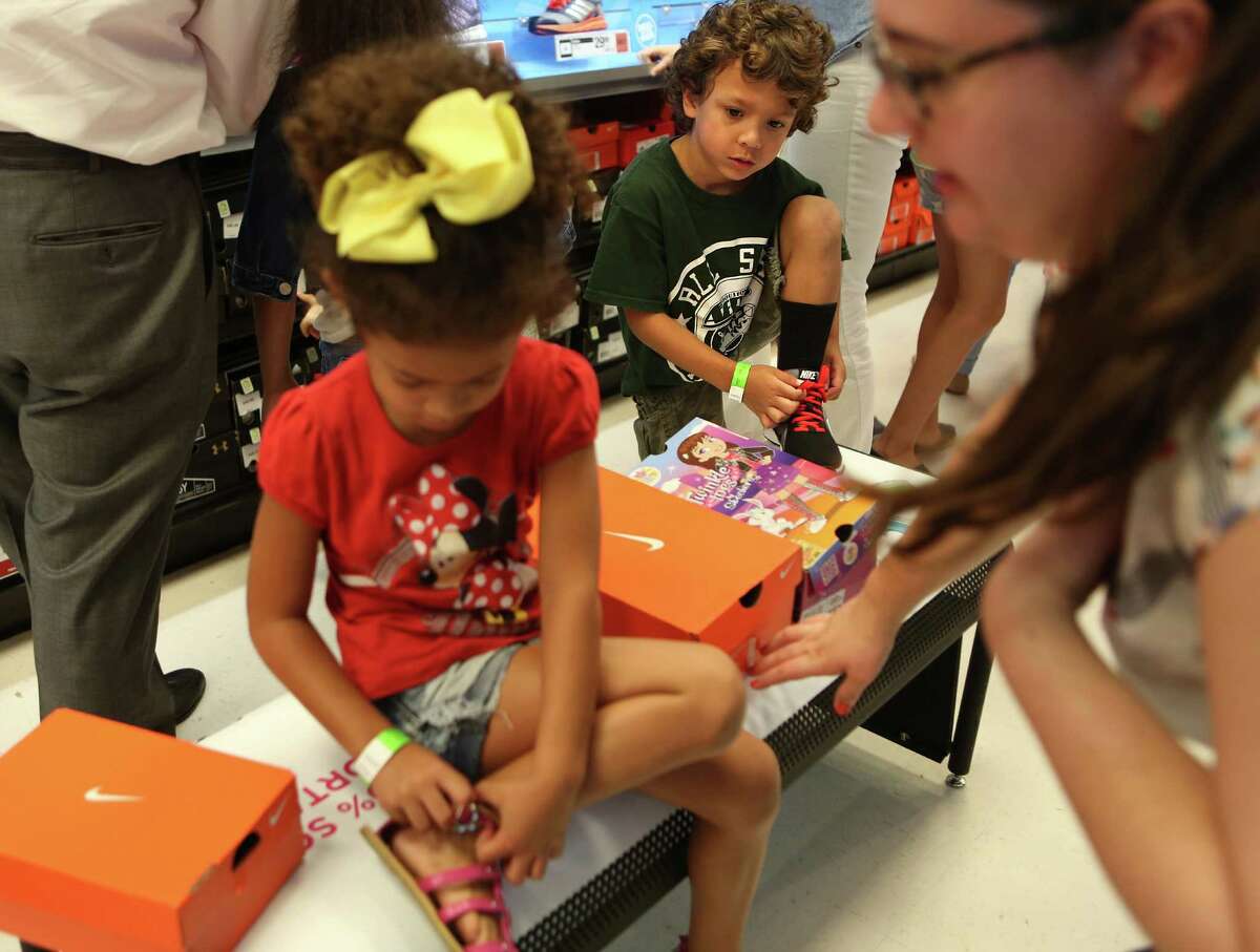 Kayla Gunter, 5, and Fabian Sherk, 6, try on new shoes during the "shoe party" at Houston's Sports Authority on Post Oak Boulevard on Monday, Aug. 18, 2014, in Houston. 