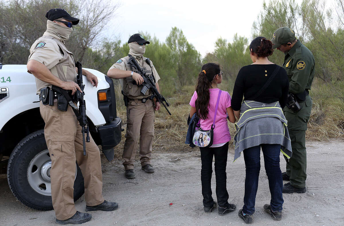 Central American immigrants are questioned by a U.S. Border Patrol agent, with Texas game wardens standing guard, after they crossed the Rio Grande by boat into the United States last Wednesday.
