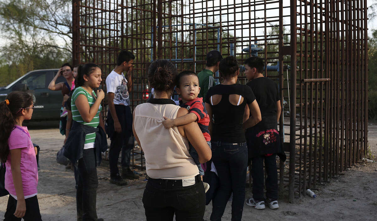 Maria Bertalina Ramirez of Honduras, holding her son, and other immigrants are guided to a clearing to be questioned.