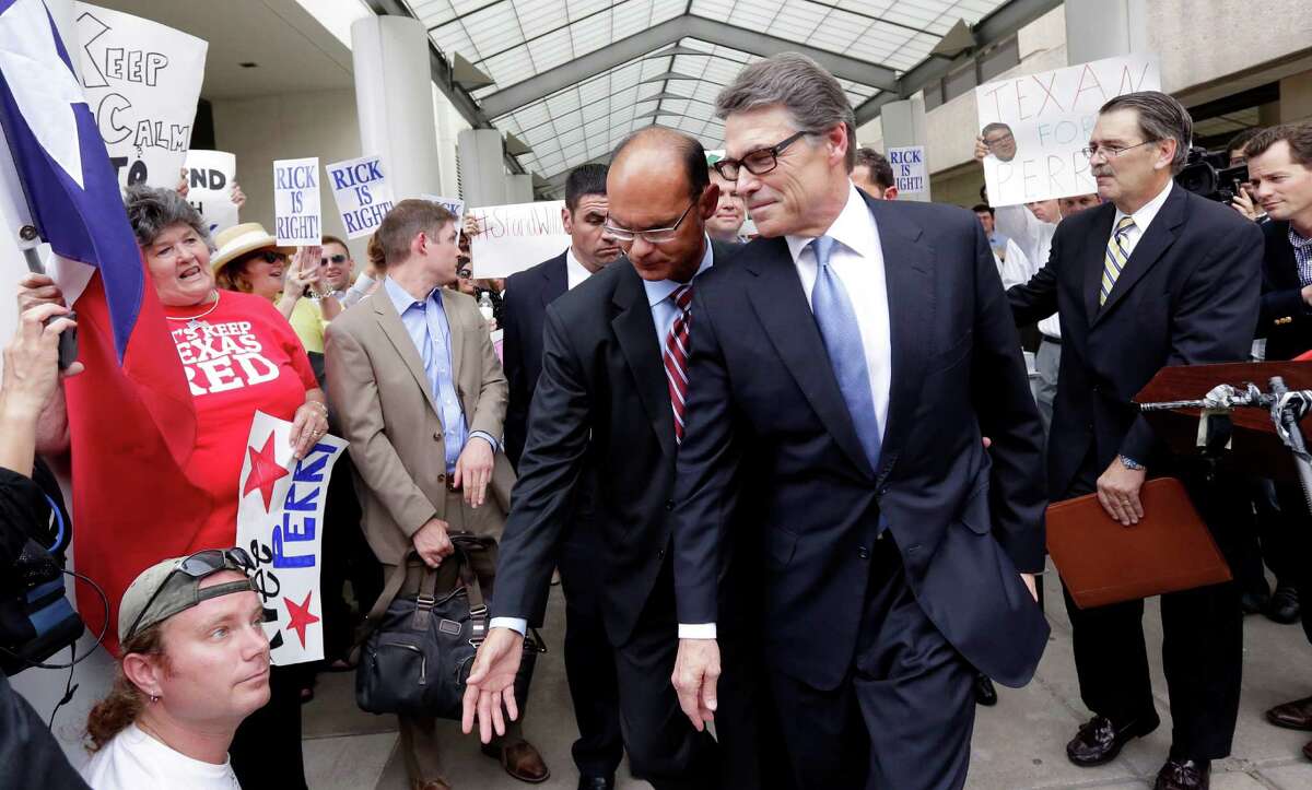 Texas Gov. Rick Perry, front right, is escorted away from the Blackwell Thurman Criminal Justice Center, Tuesday, Aug. 19, 2014, in Austin, Texas. Perry has been booked on two felony counts of abuse of power for carrying out a threat to veto funding to state public corruption prosecutors. (AP Photo/Eric Gay)