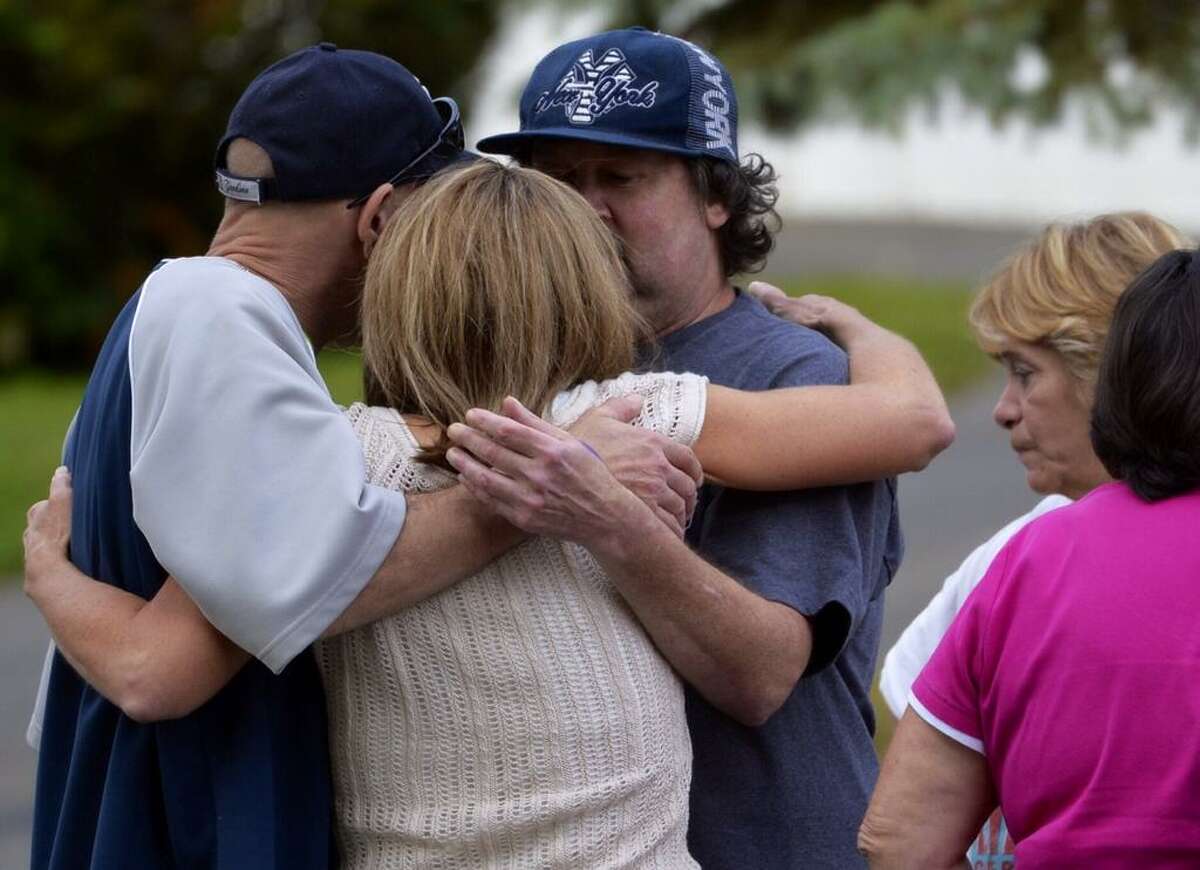 A relative of two people who were found beaten to death inside a home at 709 First Ave., in Troy, are comforted by co-workers of one of the dead. (Skip Dickstein / Times Union)