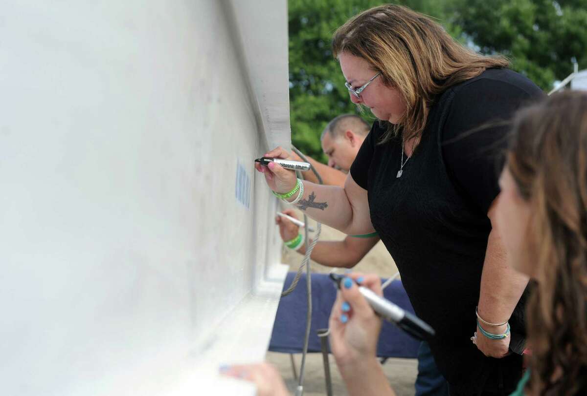 Donna Soto signs the final beam before it is set in place on the Victoria Soto School at Stratford Academy Thursday, Aug. 21, 2014 in Stratford, Conn. Her daughter Victoria Soto was killed in the Sandy Hook Elementary School shooting.