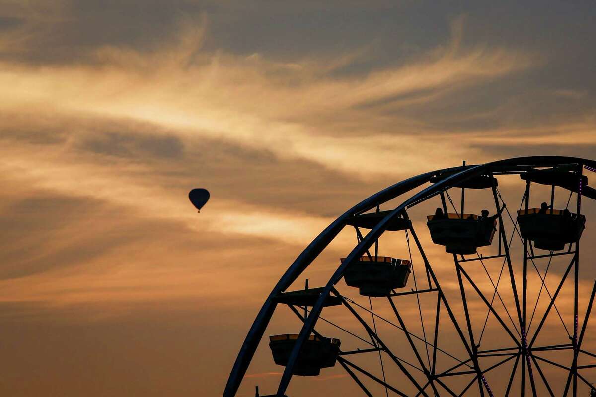 A ride is shown as a hot air balloon glides overhead during the first weekend of the Evergreen State Fair in Monroe. The annual fair continues through September 1. Photographed on Saturday, August 23, 2014.