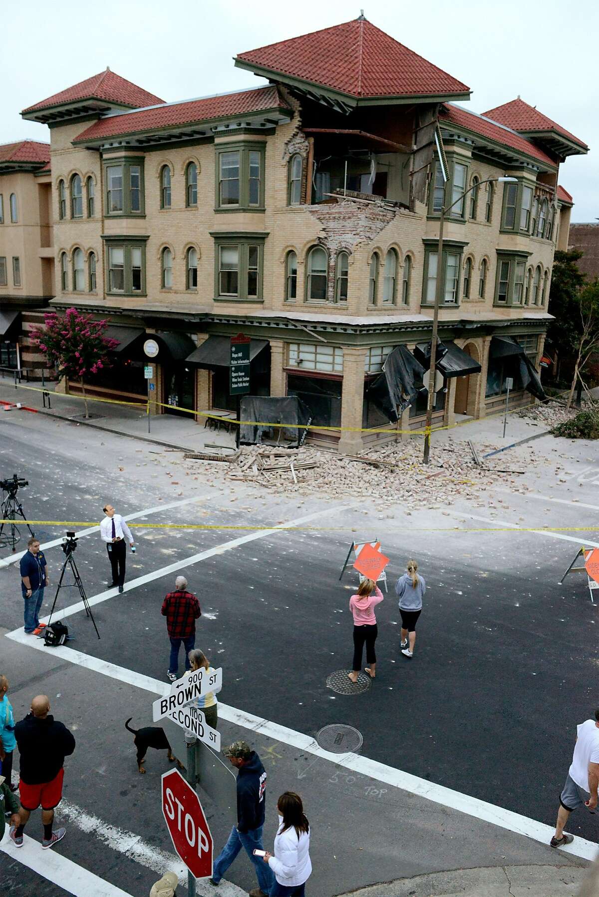 Spectators survey the damage to a building at the corner of Brown Street and Second Street in Napa, California, after an earthquake measuring 6.0 on the Richter scale struck in the early morning of August 24, 2014.