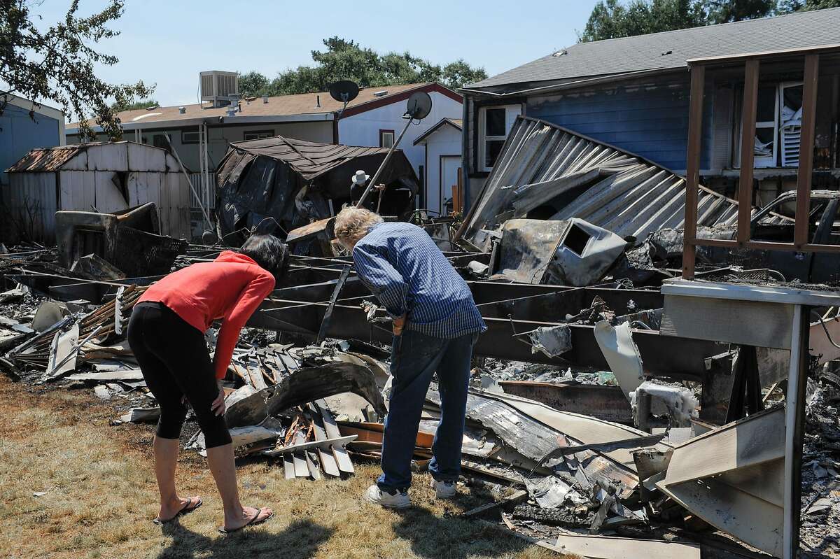 Two residents inspect damage to a burned out mobile home along Mark Way inside the Napa Valley Vedder Community Mobile Home park on August 25, 2014 in Napa, CA.